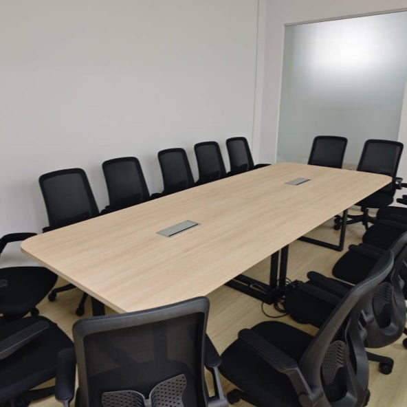 Conference room with a long wooden table and black chairs.